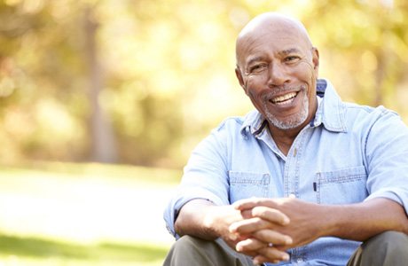 Smiling man sitting outside after getting dental implants