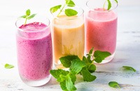 three colorful smoothies in a row with various herbs