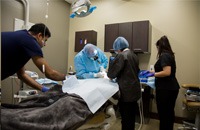 Dentist and three assistants performing dental implant surgery