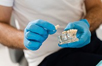 Dentist holding a dental crown and a model of a dental implant